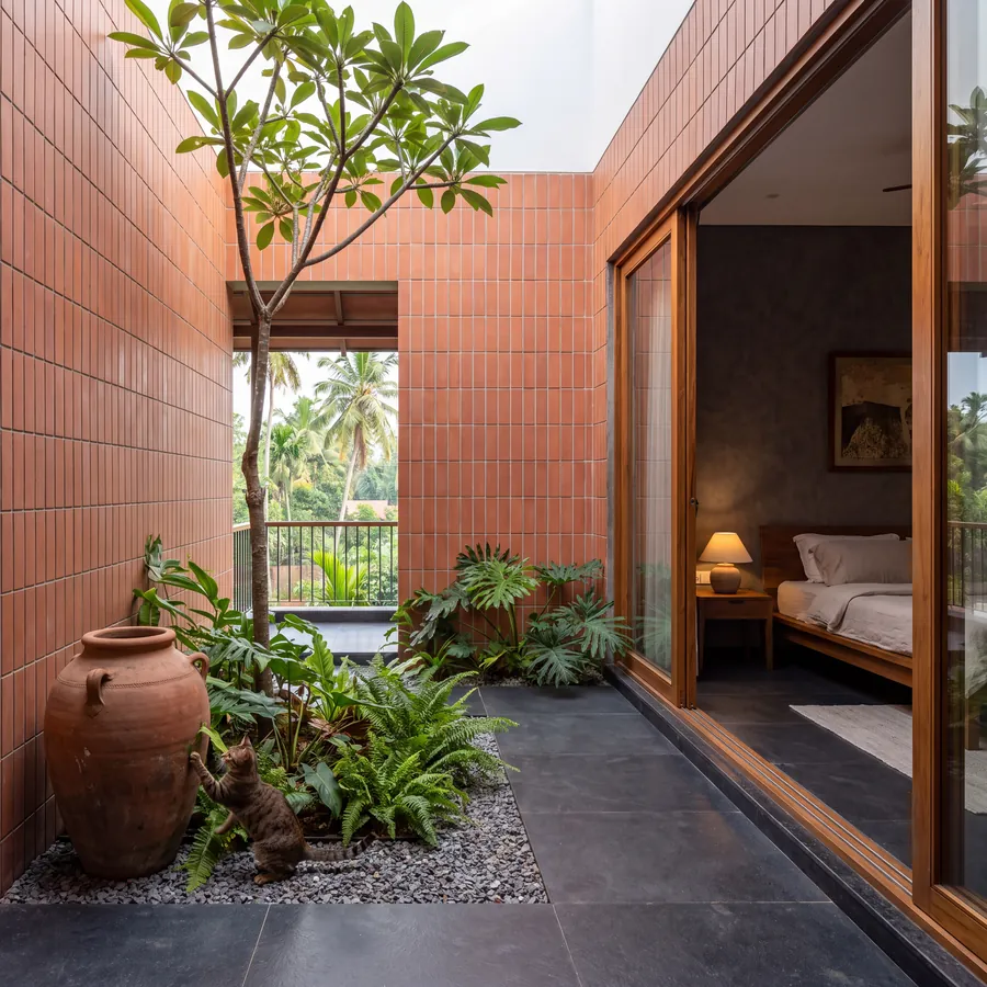 The Courtyard House: terracotta-clad light court with a tree beside the bedroom