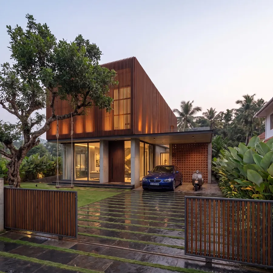 Timber Screen House by Claycode Architects: timber-slatted facade glowing at dusk with brick jali carport