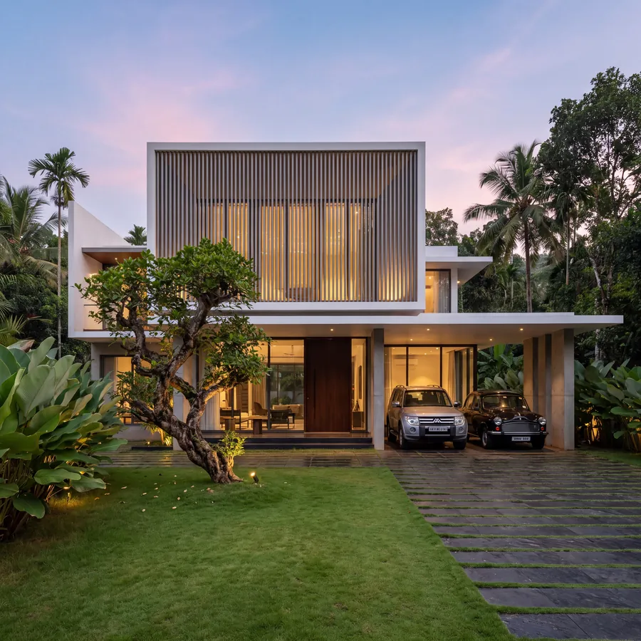 Lantern House by Claycode Architects: white house with a finned facade glowing at dusk